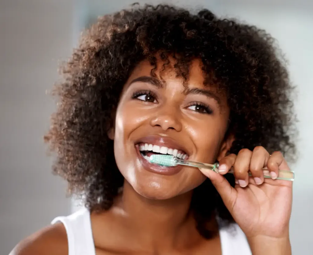 Mujer feliz cepillándose los dientes como parte de su rutina de higiene oral diaria