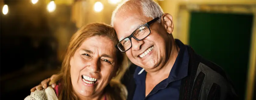 Pareja de adultos mayores sonriendo felices con prótesis dentales completas